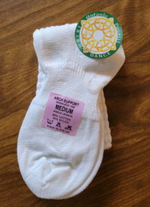 A pair of pacelli poodle socks with arch support and a pink sticker